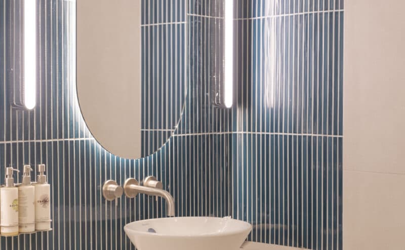 Changing room with lit mirror and tiled wall